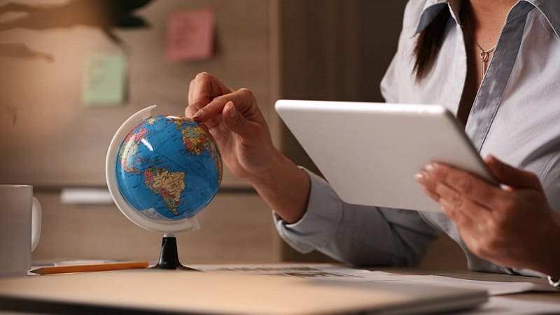 زن در حال بررسی کره زمین برای یافتن مقصد کاری مناسب